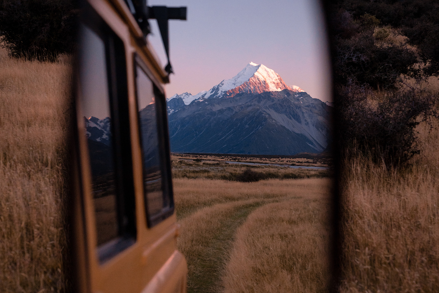 Van-Life During a Pandemic: Image of a rearview mirror of the van with a reflection of a beautiful snowcapped mountain. 