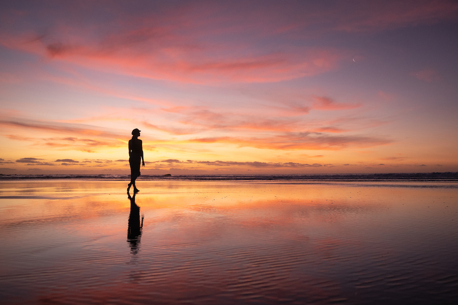 Van-Life During a Pandemic: Beautiful image of woman walking solo on the shore during an amazing sunset. 