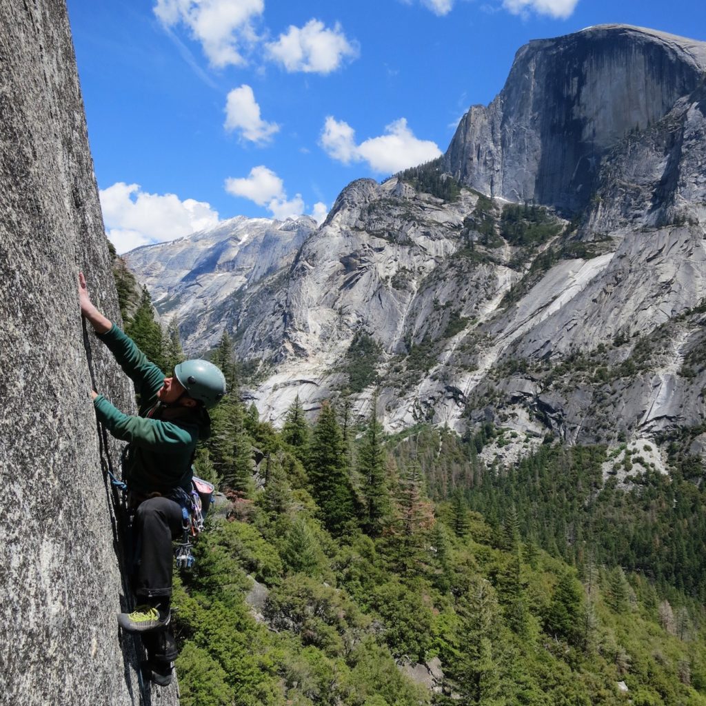 Rock climber in Yosemite climbing with image of Half Dome in the background. Stewardship during COVID-19