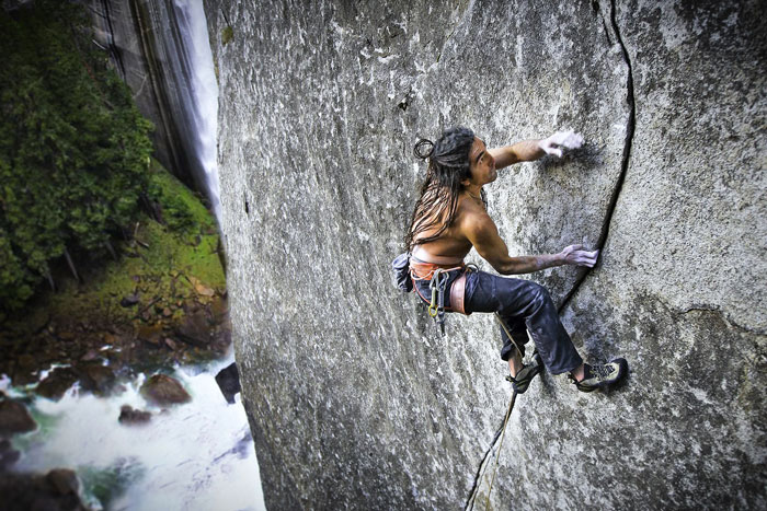 Male climber climbing face of granite rock.