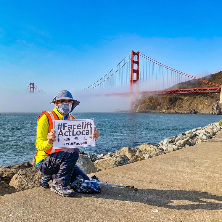Person holding a Facelift ActLocal sign by the Golden Gate Bridge