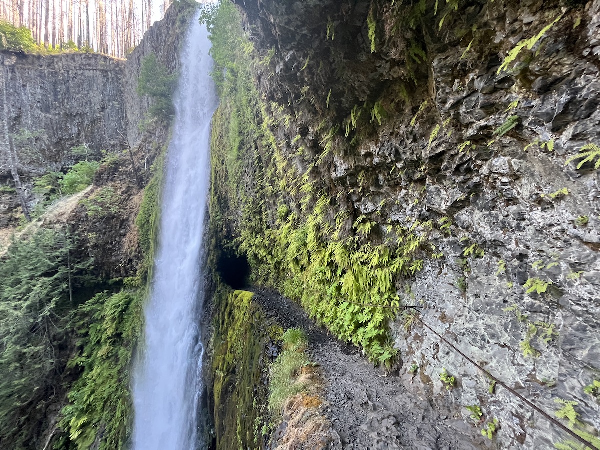 Hikers trek toward and then behind the well-named Tunnel Falls