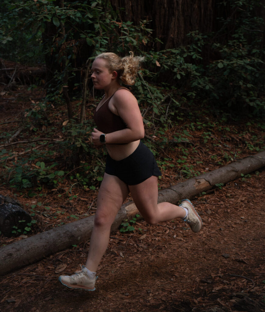 Author Ella Suring running through redwoods.