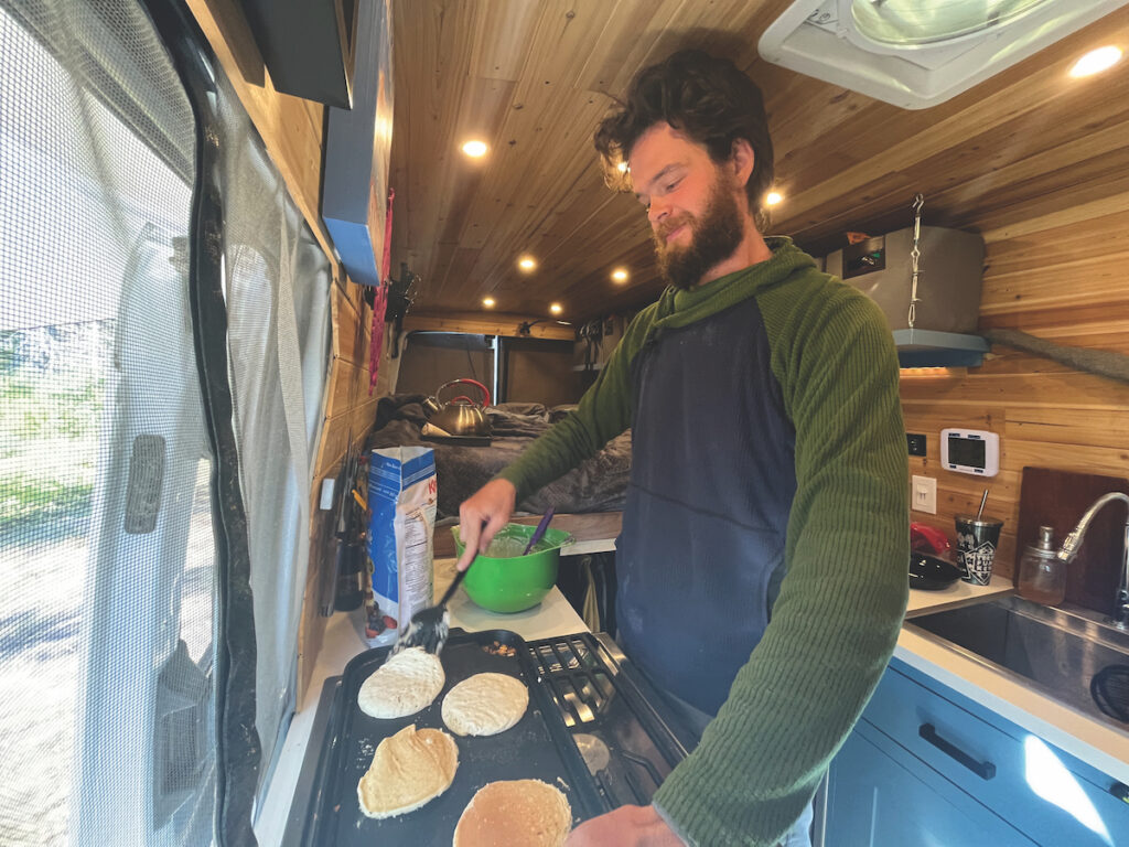 A trail angel cooking pancakes in his van for hikers.