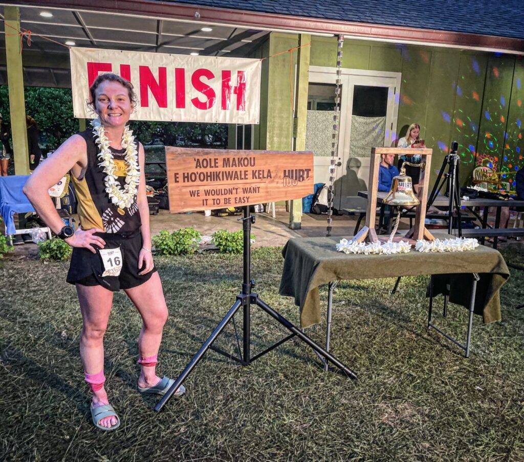 Alyssa posing at the HURT 100 finish line after the race